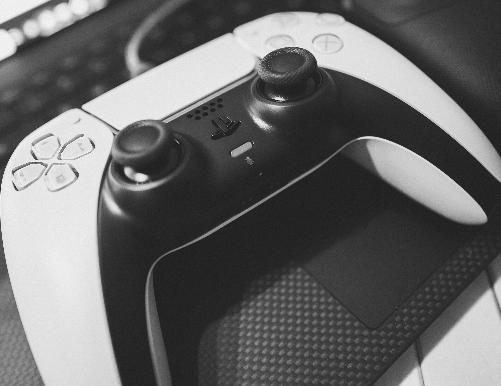 Real photograph of a white and black PlayStation 5 DualSense controller, with both analog sticks visible